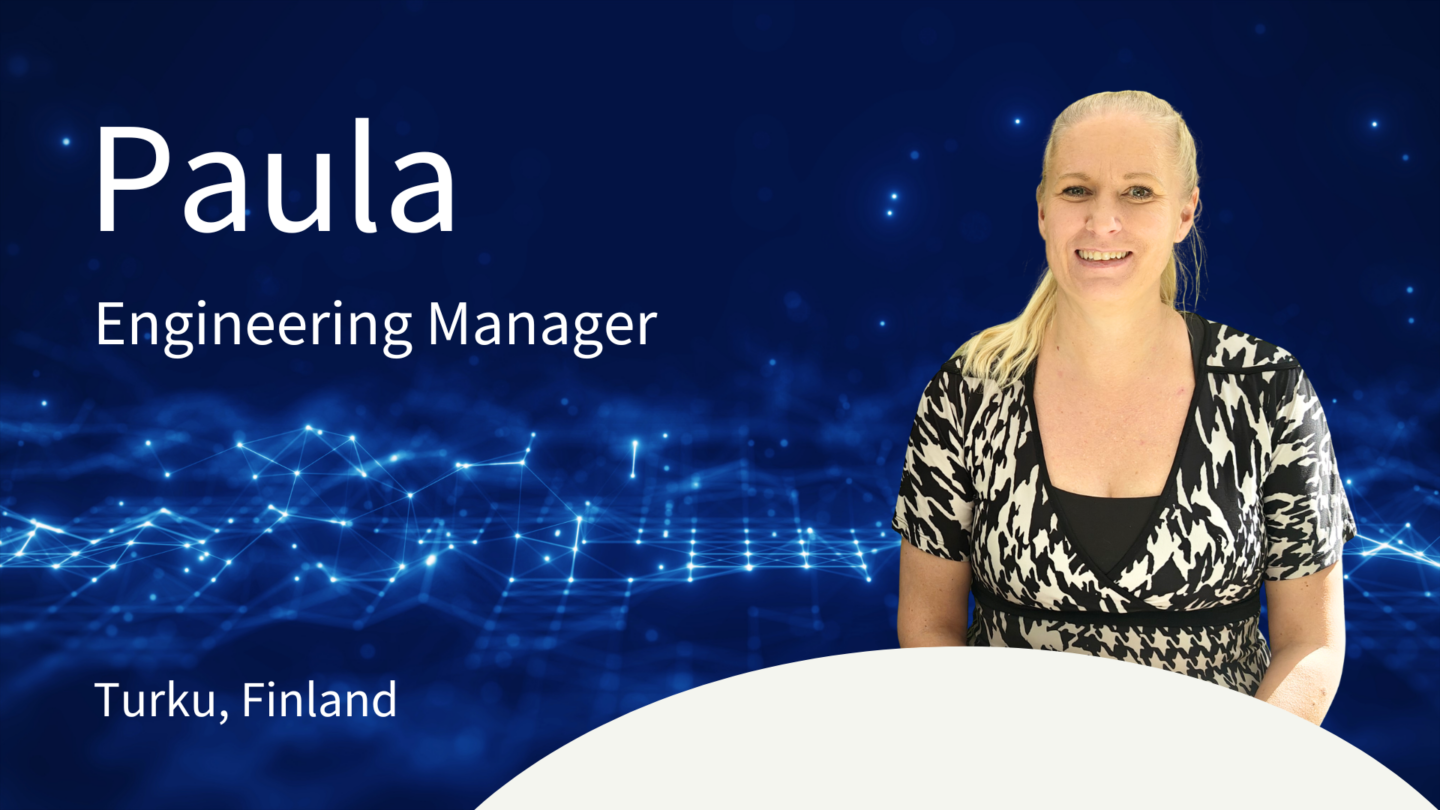 Hymyilevä Paula istumassa pöydän takana.